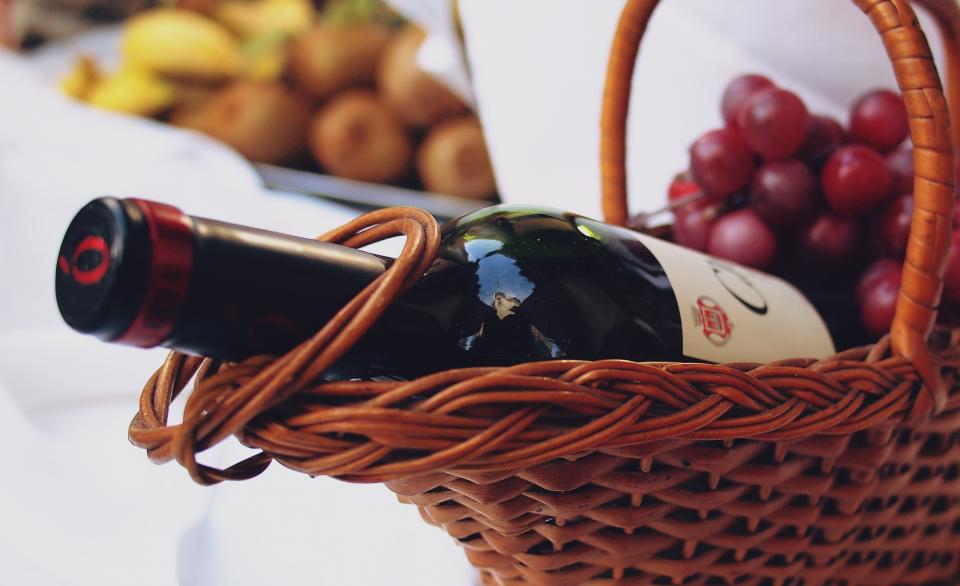 Botella de vino tinto en una cesta con uvas